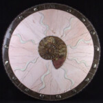 Circle of Spirals <br>
22" diameter, 2004<br>
Ammonite, marble, pyritized ammonites, handmade tile A round plate with a shell on it.