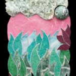 When Prehnite Met Rhodo <br>
10.5" x 18", 2009 <br>
Prehnite crystal, fuchsite with ruby sphere, rhodonite, amazonite, quartz, dumortierite, maw sit sit jade, mariposite, epidote A collage of leaves and rocks with a ball in the center.