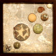 Earth Sampler Series X: Septarian and Calcite II <br>
13" x 13", 2014 <br>
Conglomeritic marble; septarian nodule, calcite crystals; spheres of serpentine, orbicular jasper, calcite, serpentine with pyrite, unakite; fossil ammonite and staurolite crystal A group of different types of rocks on top of a table.