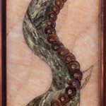 Ammonite Flow <br>
13.5" x 37.75", 2016 <br>
Onyx, marble, septarian nodules, serpentinite, fossil ammonites, Cherry Creek jasper sphere, vanadinite crystal, botryoidal hematite A picture of an octopus tentacle in a frame.