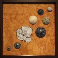 Earth Sampler Series XVII: Drusy Cluster <br>
13" x 13", 2017 <br>
Marble; chalcedony roses; drusy quartz; spheres of dumortierite, rainforest rhyolite, graphic gabbro, kambaba jasper, agate & jasper A group of balls and shells on a table.