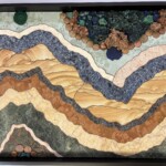 Beyond the Periphery III <br>
2024 (October) <br>
Marble, limestone, sodalite syenite, liesegang banded sandstone, granite, metasomatite; specimens of banded malachte, copper and copper "buttons", "sputnik" aragonite, azurite/malachite, and azurite concretion. A close up of a quilt with many different colors