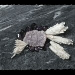 Pocket XV: Amethyst Splay <br> 10" x 19 3/4" x 2 1/2", 2020 <br> Banded marble, scolecite, amethyst drusy, tumbled amethyst A piece of rock with feathers on it.