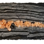 Pocket 8: Stilbite Sactuary - Surprise in the Depths <br>
23.25” x 9.5” x 2.5”, 2017 <br>
Banded marble; crystals of stilbite, pyrolusite & quartz geodes A piece of wood with some kind of food on it