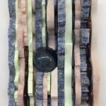 Waves V: Echoing Hills <br>
5.375” x 9.1”, 2018 <br>
Sodalite syenite, marble, tiger’s eye stone discs, magnesite, quartzite stone discs,
Dumortierite sphere A close up of the bottom part of a sculpture