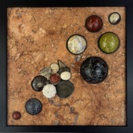 Earth Sampler Series XXVIII: Fossil Vignette 2 <br>
13" x 13", 2023 <br>
Travertine; Spheres of: jasper, agate, serpentinite, gabbro, dumortierite; Fossils: sharks tooth, ammonites, Placosmilia sp., horn coral, echinoderm, echinoid, pyritized ammonite A picture of some coins on the ground.