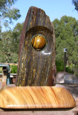 Sphere Sculpture <br> 2008 <br> Slab: tiger iron; Sphere: tiger's eye A close up of the top of a wooden sculpture