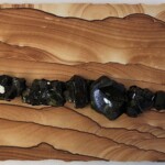 Pocket XIX: Vitreous Varnish <br> 7” x 16” x 2”, 2021 <br> Liesegang banded (Kanab) sandstone; epidote A wooden board with some rocks on it