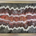 Pocket XXII: Cave Dust <br> 10.125” x 19.125”x 1.75”, 2022 <br> Crystals: realgar with orpiment
Slabs: slate, marble, agate, rhodonite, lepidolite A picture of some meat on top of a table.