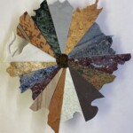 Triangles III: Ammonite Echo <br> 12” diameter, 2022 <br> Marble, travertine, ferruginous silicified shale (printstone), dumortieritic quartzite, slate, agate, metasomatite, sandstone, sodalite syenite, conglomeritic marble A circular wall sculpture of different colors and textures.