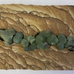 Pocket XXIII: Spring in Snow Canyon – 6.25” x 15.5” x 2”, 2023<br>Liesegang banded (Kanab) sandstone; prehnite, epidote A close up of some green rocks on the ground