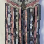 Wings VII: Rosinca - 13” x 8.75” x 2”, 2022 <br> Rhodochrosite, pyritized ammonite, quartz crystals, slate, marble, agate, rhodonite, lepidolite, pyrite A wall hanging made of strips of fabric.