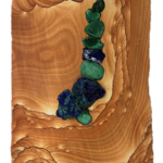 Pocket XXIV: Pools of Reflection - 22.5” x 8” x “, 2023 <br> Liesegang banded (Kanab) sandstone; malachite, azurite A wooden surface with some rocks and stones